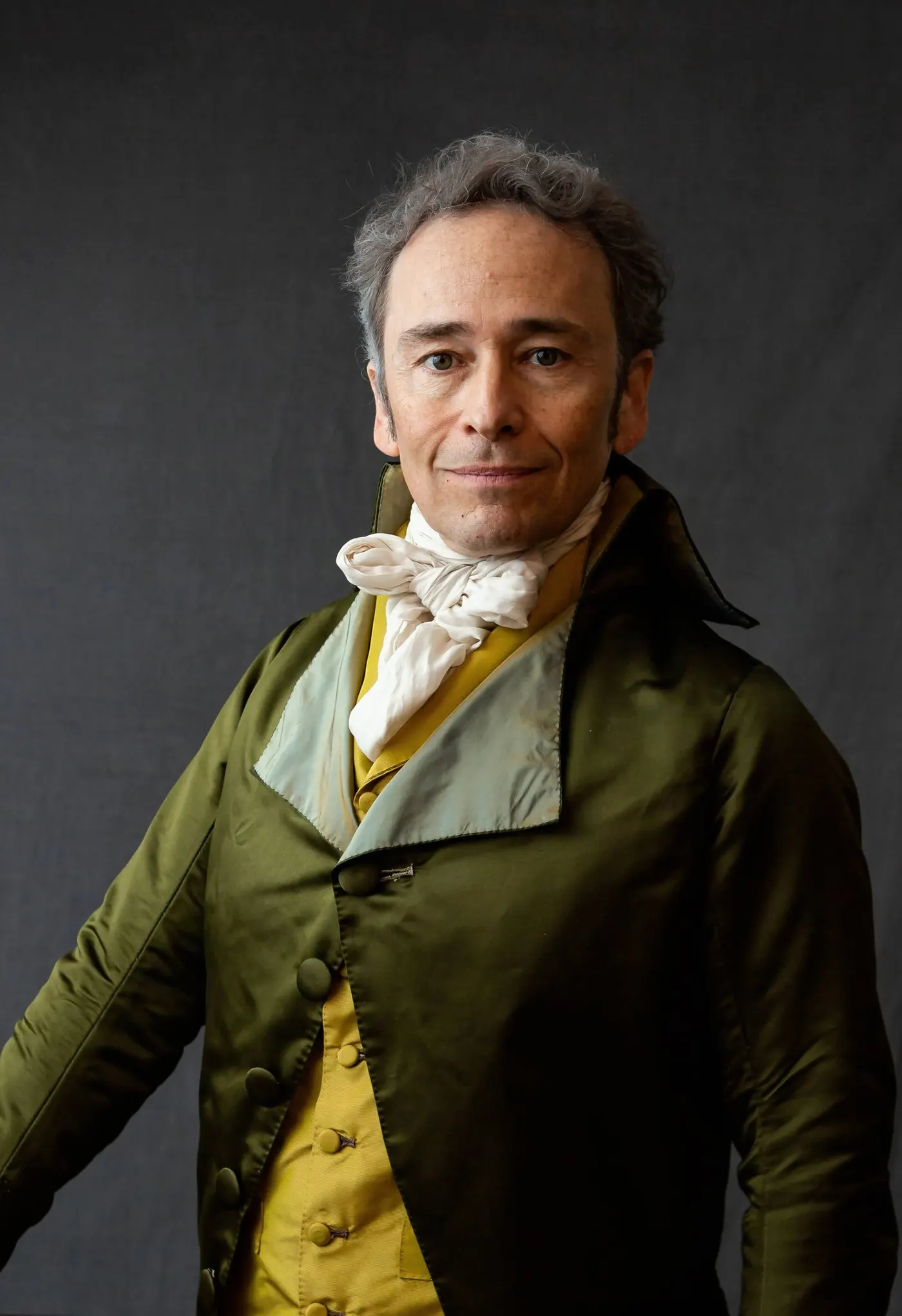 Studio portrait of Scott MacScott as Alexander Hamilton in an olive coat and yellow vest